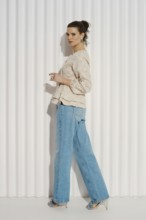 A model stands sideways with her left foot forward, wearing a casual outfit consisting of a light