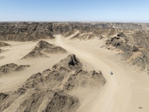 Aerial view, dry barren mountains in Moon Valley, road with car, rocky landscape ridged by erosion,