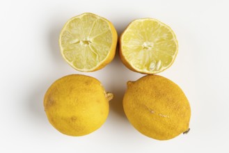 Two whole and two half old lemons on a light background