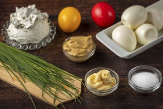 Fresh ingredients, such as herbs, cream cheese and eggs on a wooden table