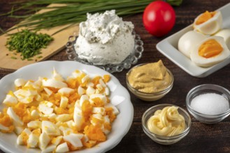 Ingredients for making egg cream with sliced eggs and cream cheese on a wooden table