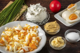 Sliced Easter eggs and fresh ingredients for a spread arranged on a wooden table