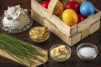 Ingredients such as colorful Easter eggs, herbs and cream cheese arranged on a wooden table