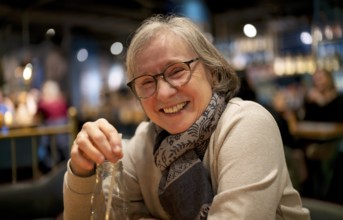 Elderly woman, portrait, glasses, gray hair, scarf, drink, straw, sitting in a bar, restaurant,