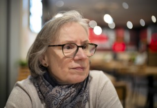 Elderly woman, portrait, glasses, gray hair, scarf, sitting in a bar, restaurant, Stuttgart,