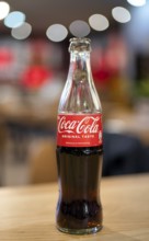 Coke, Coca-Cola, bottle, 0.3 liter, half full, half empty, standing on a table, restaurant, bar,