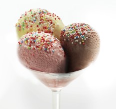 Ice cream sundae with chocolate, strawberry and vanilla, decorated with coloured sprinkles, studio