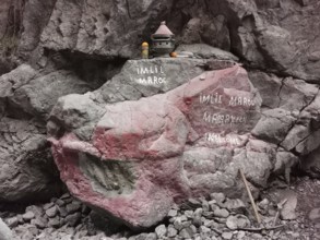 A rock with red and white inscriptions and small decorative objects, welcome, Atlas, Imlil, Morocco