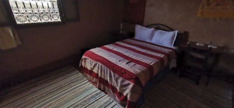 Cozy bedroom with a striped duvet cover and traditional wood decor, Morocco