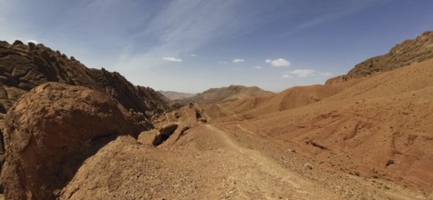 Desert hills with eroded rocks and trails under clear skies, Morocco