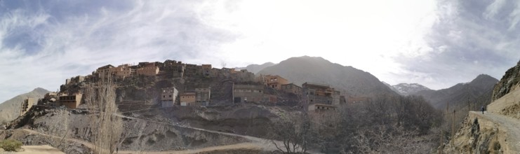 A small village on a hill surrounded by mountains under a sunny sky, panorama, Atlas Mountains,
