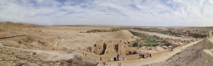 Historic buildings and an oasis in desert-like surroundings under cloudy skies, Morocco