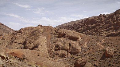Rocky hills with a person on the summit under a cloudy sky, Morocco