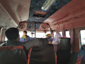 People sitting and talking in the interior of a colorful old bus, Morocco