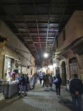 Bustling nocturnal alley in the Medina, with people under a covered path in an oriental market
