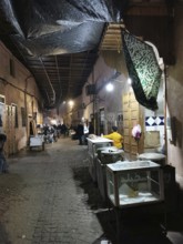 Nocturnal market alley of an oriental medina with stalls and cozy lighting, Marrakech, Morocco