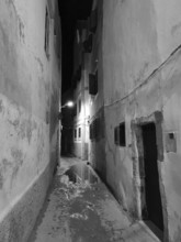 Narrow alley at night with wet floor and atmospheric lighting, monochrome, old town of Essaouira,