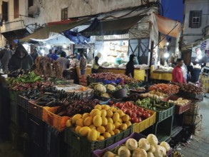 Bustling night market in the Medina with colorful stalls full of fruit and vegetables, people