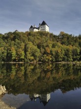Burgk Castle is reflected in the calm water of the Saale, Thuringian Forest