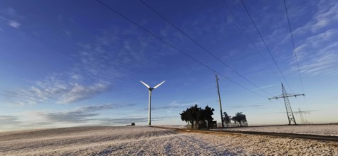 Winter landscape with wind turbine and power lines against a blue sky, Rennsteig, Frankenwald