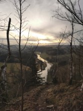 A river snakes through a hilly landscape at sunset, looking across the Saxon Saale from the