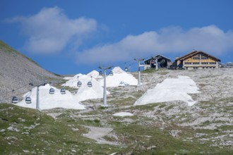 Global warming, artificial snow in piles next to cable car, Brenta, Parco Naturale Brenta-Adamello,