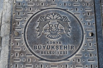 Metal manhole cover with Konya coat of arms and Turkish text, robust urban design, Gully, Konya,
