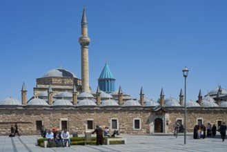 View of a large mosque with minaret and domes surrounded by people and blue sky, Mevlana Museum,
