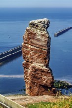 Isolated rock by the sea with a harbor wall in the background, the high-seas island of Heligoland