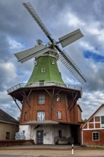 Historic brick windmill with green roof under cloudy sky, An old historic windmill near Stade