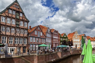 Half-timbered facades and terraces on the river with cyclists and cloudy sky, The old town of Stade