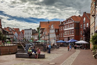 People sitting on cafe terraces along the river under a cloudy sky, The old town of Stade