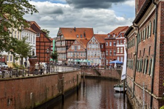 Boats on the river surrounded by half-timbered houses with brick walls under a cloudy sky, The old