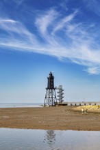 A lighthouse on the beach under a clear sky with picturesque clouds, Die Kugelbake von Cuxhaven