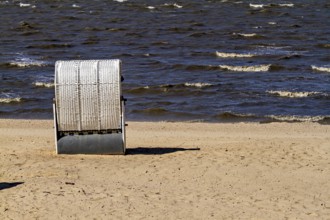 A single white beach chair stands alone on the quiet and windy beach, beach chairs on the beach in