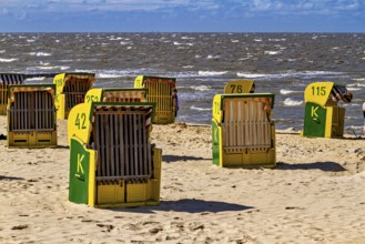There are some beach chairs on a bright beach with a sea background under a blue sky, beach chairs
