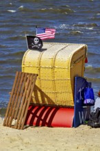 A single yellow beach chair on the beach with American and pirate flag in the wind, beach chairs on