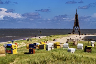 Beach on the North Sea coast with lighthouse and beach chairs under a blue sky, beach chairs on the