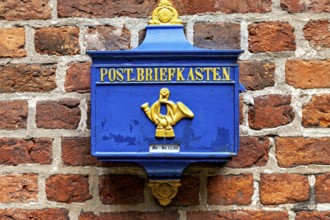 A blue yellow mailbox on a brick wall, nostalgic design, historic blue mailbox