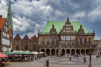 Market square with Renaissance buildings and cafés, people under a dramatic sky, The Town Hall of