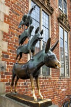 Bronze sculpture of the Town Musicians in front of a brick wall with windows, The Bremen Town