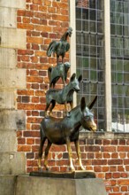 The Town Musicians of Bremen as a bronze sculpture in front of an old wall with windows, The Bremen