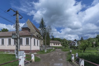 Village street with abandoned 16th century Lutheran fortified church in Tobsdorf, Romanian Dupus,