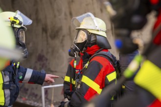 Firefighters talking, equipped with respiratory protection and protective equipment, in a tunnel,
