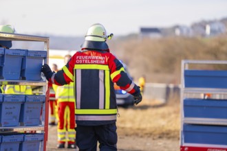 A firefighter in uniformed clothing stands on a railway line with equipment, fire department