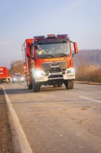A fire truck on a country road with other emergency vehicles in the background at morning light,