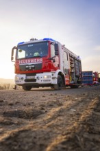 A fire truck stands on a country road in patrol light, firefighters ready to act, fire brigade