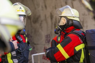 Two firefighters wearing respirators talking, ready for deployment in a tunnel, fire brigade