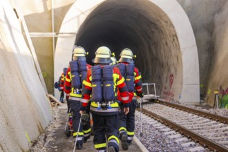 Firefighters in protective clothing enter a rail tunnel for a mission, fire brigade exercise on the