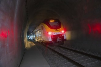 Modern train passes through illuminated tunnel breaking through darkness, fire brigade exercise on